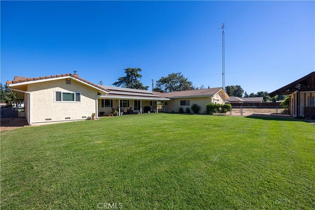 back of property featuring a yard and solar panels