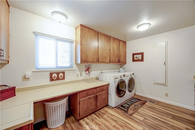 washroom with cabinets, washing machine and clothes dryer, light hardwood / wood-style flooring, and a textured ceiling