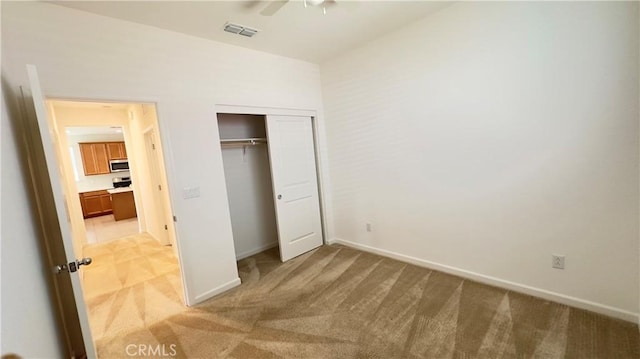 unfurnished bedroom featuring ceiling fan, a closet, and light carpet