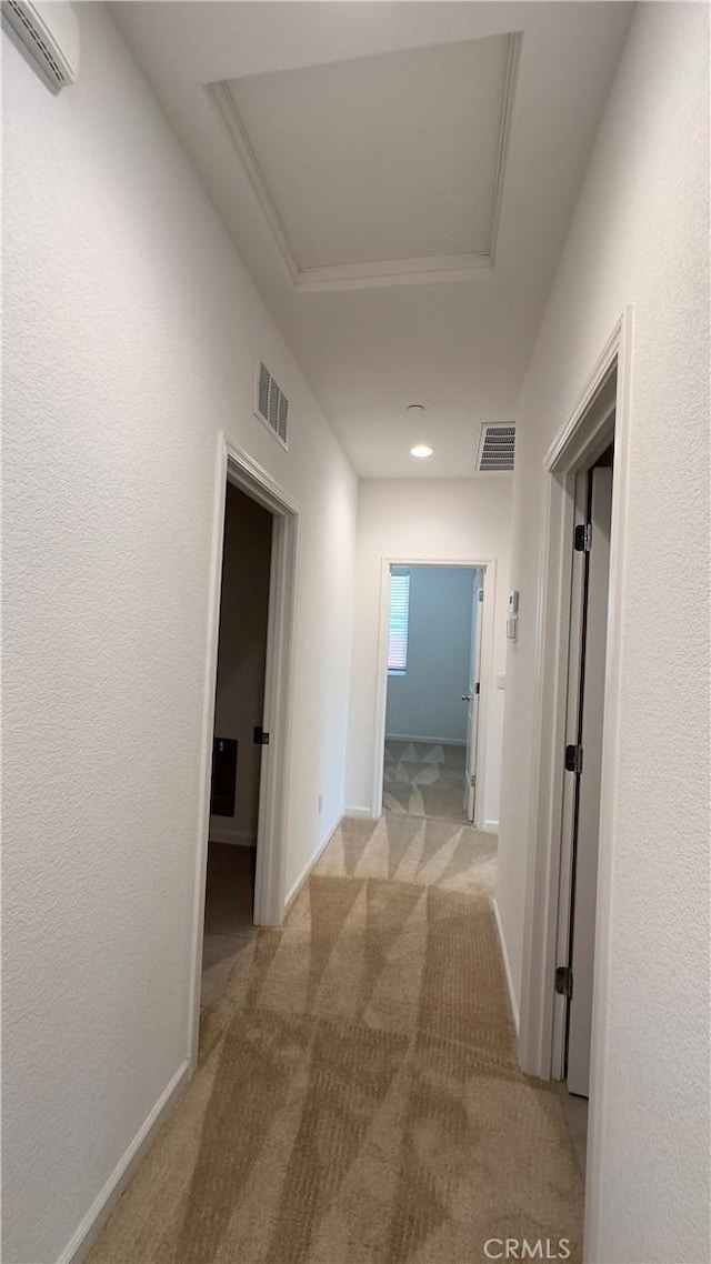 corridor featuring light colored carpet and a wall unit AC