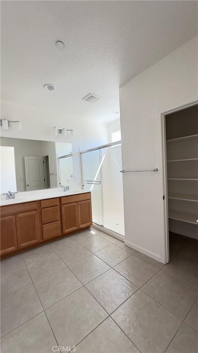 bathroom featuring vanity, a shower with shower door, tile patterned floors, and a textured ceiling