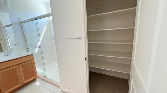 bathroom featuring vanity, a shower with shower door, and tile patterned flooring