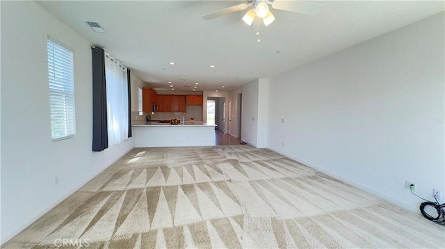 unfurnished living room featuring ceiling fan and light carpet