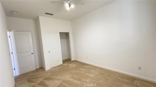 unfurnished bedroom with light carpet, a closet, and ceiling fan