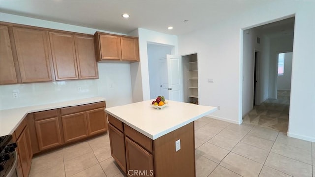 kitchen with range with gas stovetop, a kitchen island, and light tile patterned floors