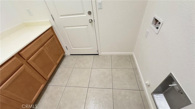 laundry area with light tile patterned floors, hookup for a washing machine, and cabinets