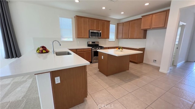 kitchen with appliances with stainless steel finishes, kitchen peninsula, sink, and light tile patterned floors