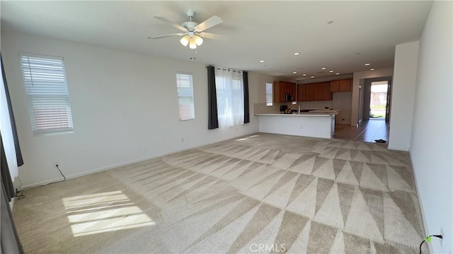 unfurnished living room featuring ceiling fan and light carpet