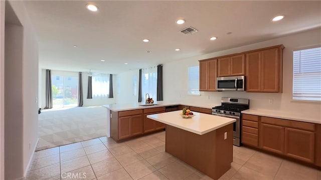 kitchen featuring stainless steel appliances, kitchen peninsula, sink, and a kitchen island