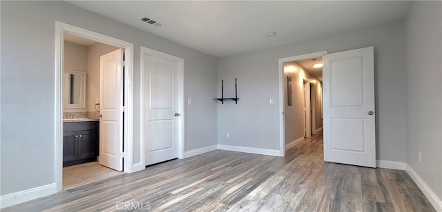 unfurnished bedroom featuring light hardwood / wood-style flooring and ensuite bath