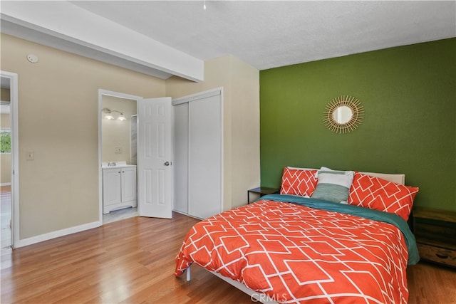 bedroom with wood-type flooring, a closet, beamed ceiling, a textured ceiling, and ensuite bathroom