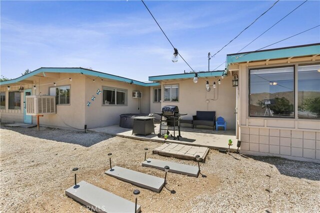 rear view of property with a wall mounted air conditioner and a patio area