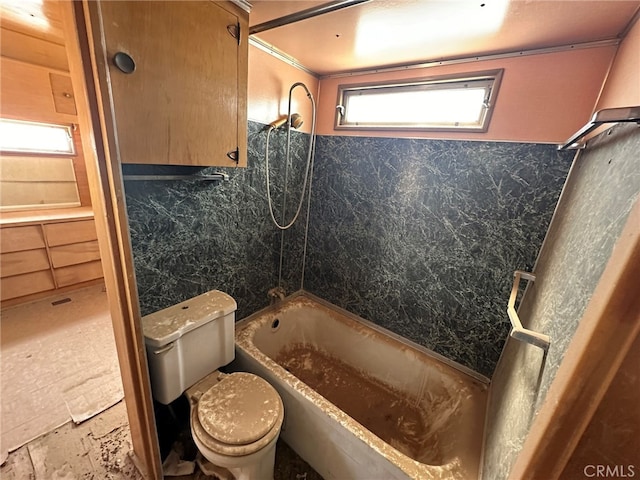 bathroom featuring tile walls, bathing tub / shower combination, and toilet