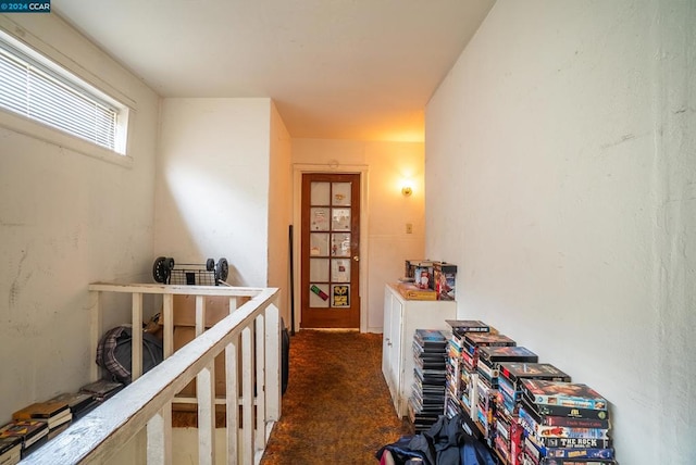 hall featuring dark colored carpet