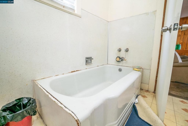 bathroom with a tub to relax in and tile patterned floors