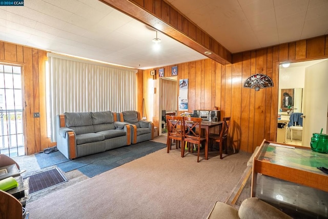 carpeted living room featuring wood walls and beam ceiling