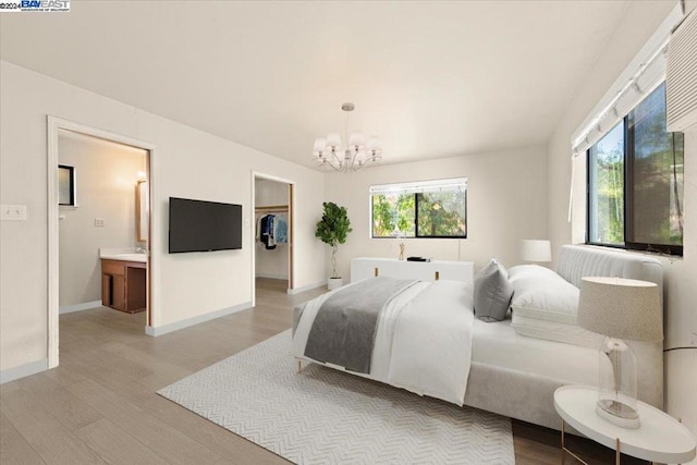 bedroom with multiple windows, light hardwood / wood-style flooring, ensuite bathroom, and a chandelier