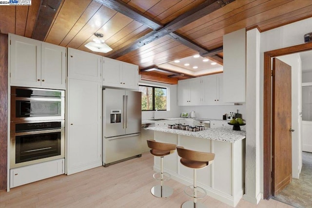 kitchen with light stone countertops, appliances with stainless steel finishes, wood ceiling, and white cabinetry