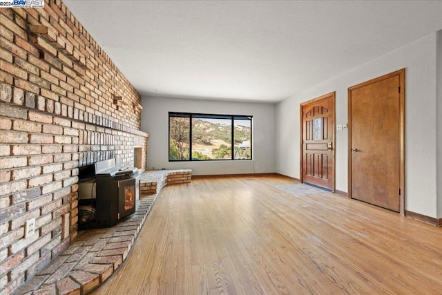 unfurnished living room featuring light hardwood / wood-style floors and a wood stove