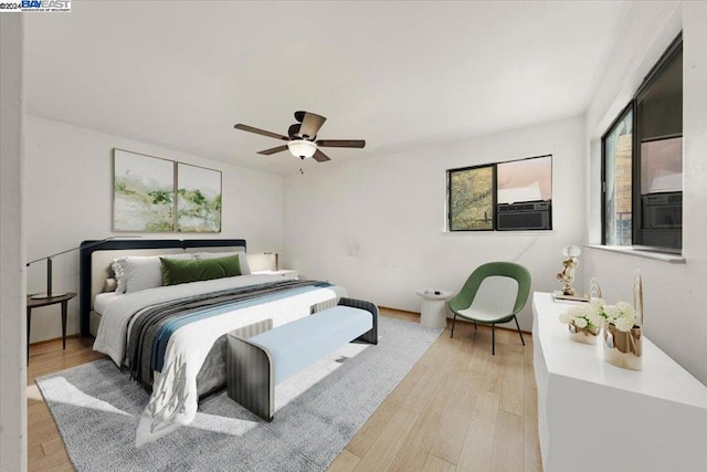 bedroom with light wood-type flooring, ceiling fan, and cooling unit