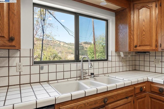 kitchen featuring tile counters, decorative backsplash, sink, and plenty of natural light