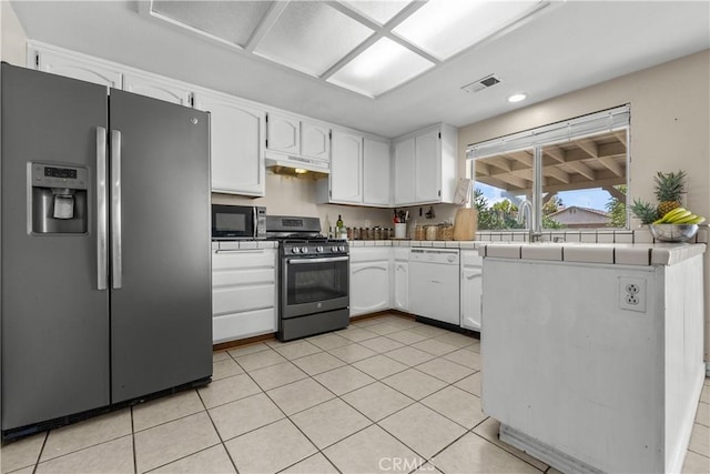 kitchen featuring stainless steel appliances, white cabinetry, tile counters, and light tile patterned flooring