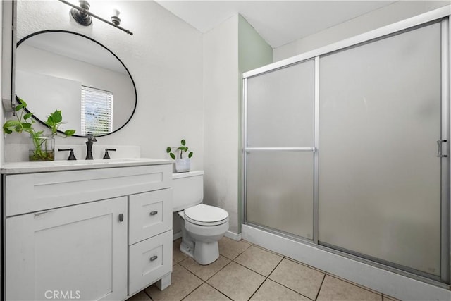 bathroom with tile patterned flooring, vanity, toilet, and a shower with shower door