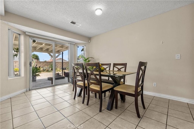 dining space with light tile patterned floors and a textured ceiling