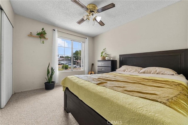 carpeted bedroom with a textured ceiling, a closet, and ceiling fan