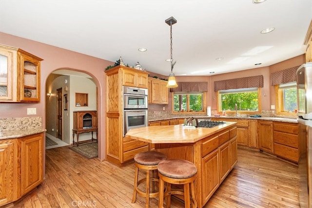 kitchen with light wood-type flooring, stainless steel appliances, a kitchen island, and wooden counters