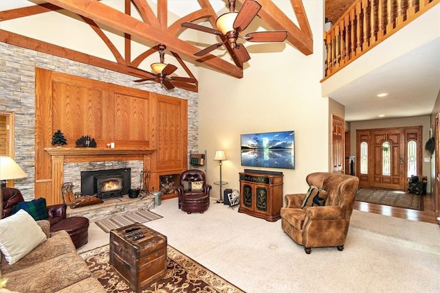 carpeted living room featuring high vaulted ceiling, ceiling fan, beamed ceiling, and a fireplace