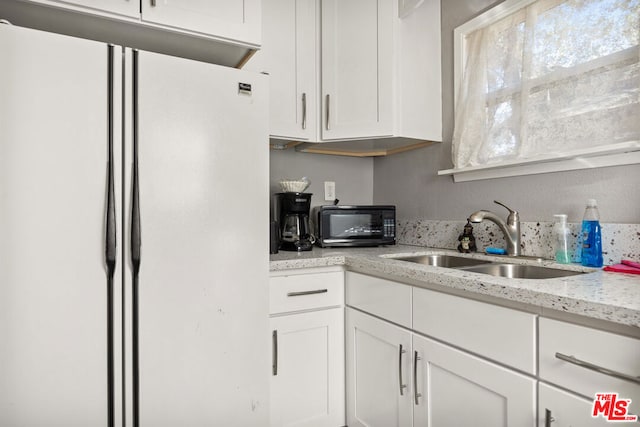 kitchen featuring white cabinets, sink, light stone counters, and white refrigerator