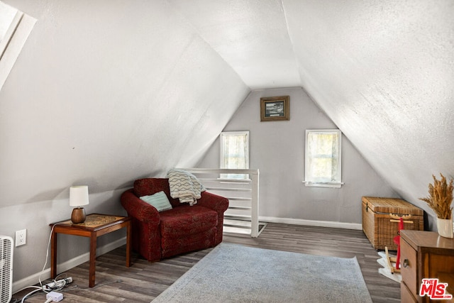 living area featuring a textured ceiling, dark hardwood / wood-style floors, and vaulted ceiling