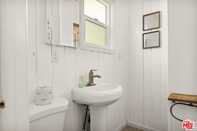 bathroom featuring wooden walls and toilet