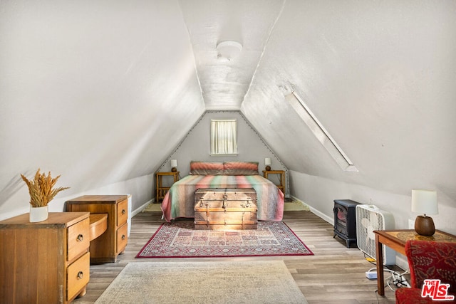 bedroom with hardwood / wood-style flooring and vaulted ceiling with skylight