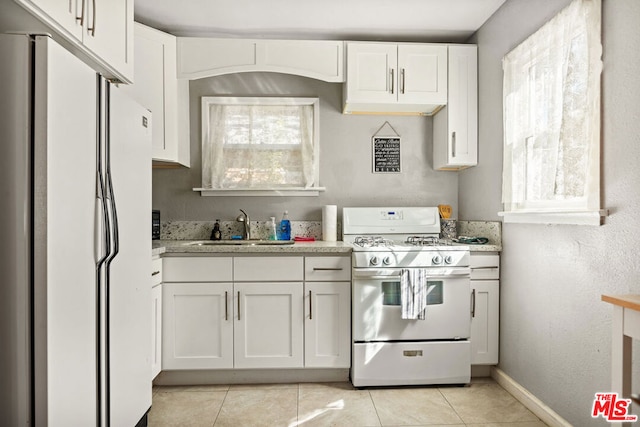 kitchen featuring white cabinetry, light stone counters, white appliances, light tile patterned floors, and sink