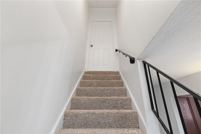 stairs featuring carpet floors and a textured ceiling