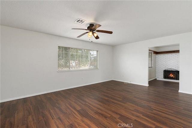 unfurnished living room with ceiling fan, dark hardwood / wood-style flooring, and a brick fireplace