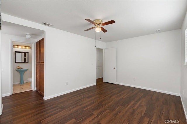 unfurnished bedroom featuring dark hardwood / wood-style floors, ceiling fan, and ensuite bathroom