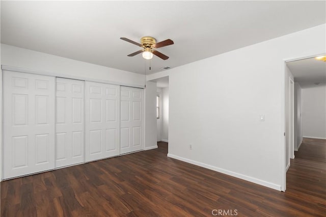 unfurnished bedroom with ceiling fan, dark wood-type flooring, and a closet