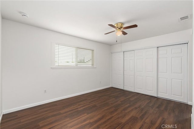 unfurnished bedroom with ceiling fan, dark wood-type flooring, and a closet