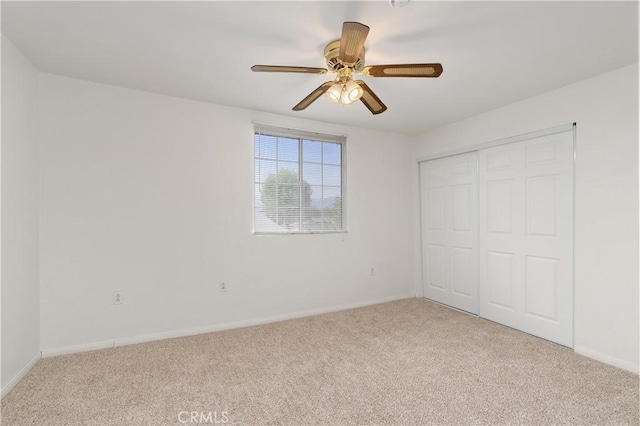 unfurnished bedroom featuring ceiling fan, a closet, and light carpet