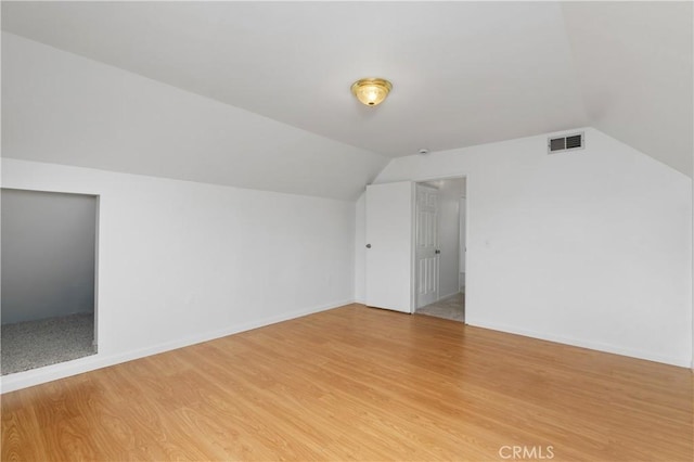 additional living space with lofted ceiling and hardwood / wood-style flooring