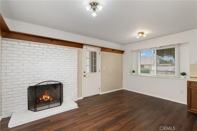 unfurnished living room featuring dark hardwood / wood-style floors and a brick fireplace