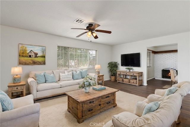 living room featuring hardwood / wood-style floors, ceiling fan, and a brick fireplace