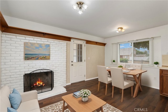 living room featuring a brick fireplace and dark wood-type flooring