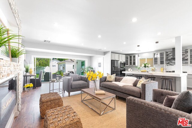 living room featuring a stone fireplace, light wood-type flooring, and sink