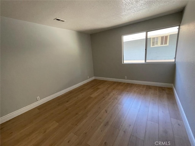 unfurnished room with wood-type flooring and a textured ceiling