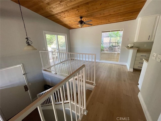 hallway with light hardwood / wood-style floors, vaulted ceiling, and wooden ceiling