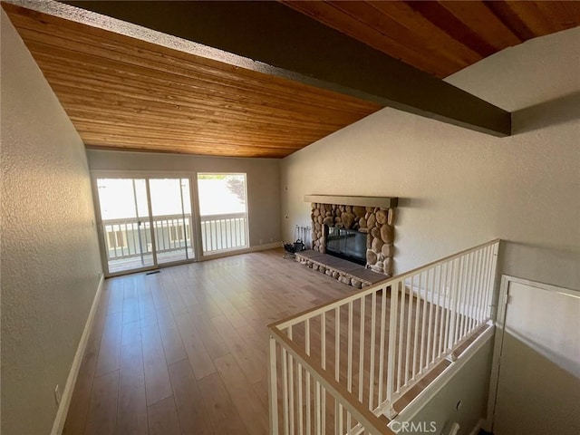 unfurnished living room featuring vaulted ceiling with beams, wood-type flooring, wood ceiling, and a fireplace